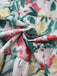 Close-up of colorful floral fabric with green, red, yellow, and pink flowers on a white background.