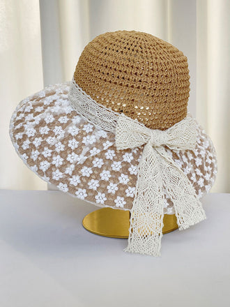 Straw hat with a white lace ribbon on a neutral background