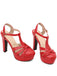 A pair of striking red high-heeled sandals designed with a classic T-strap and a sturdy platform.